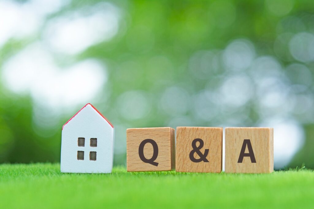 緑の芝生に白いミニチュアの家と「Q & A」の木製ブロック。住宅売却や相続等に関するQ&A。