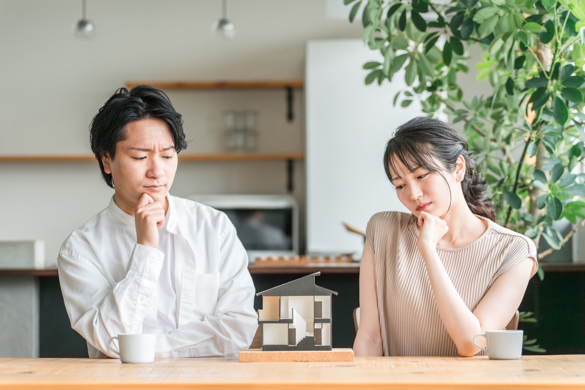 住宅模型を見てマイホームの間取りを検討する若い夫婦