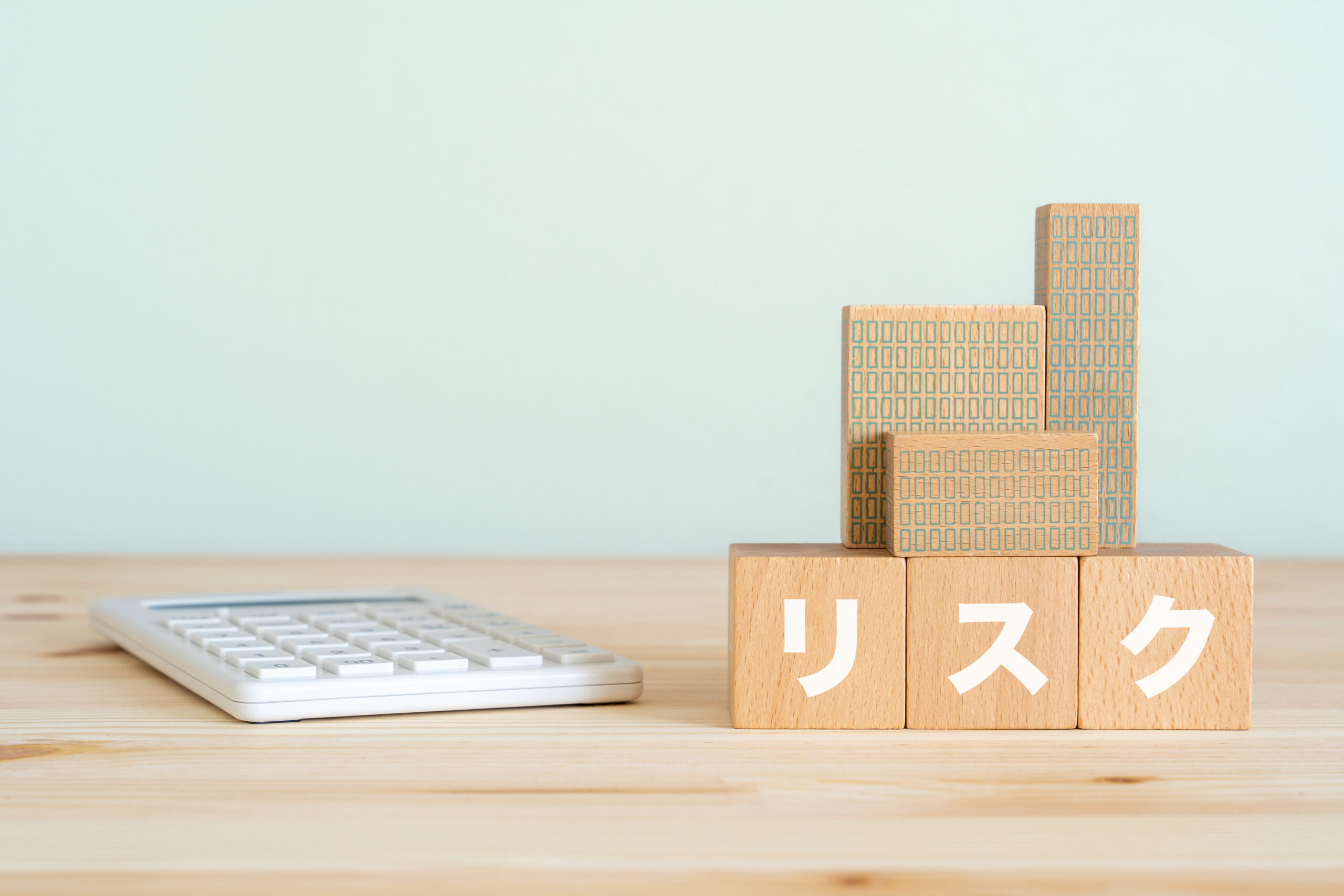 リスクと書かれたブロック、不動産の模型、電卓