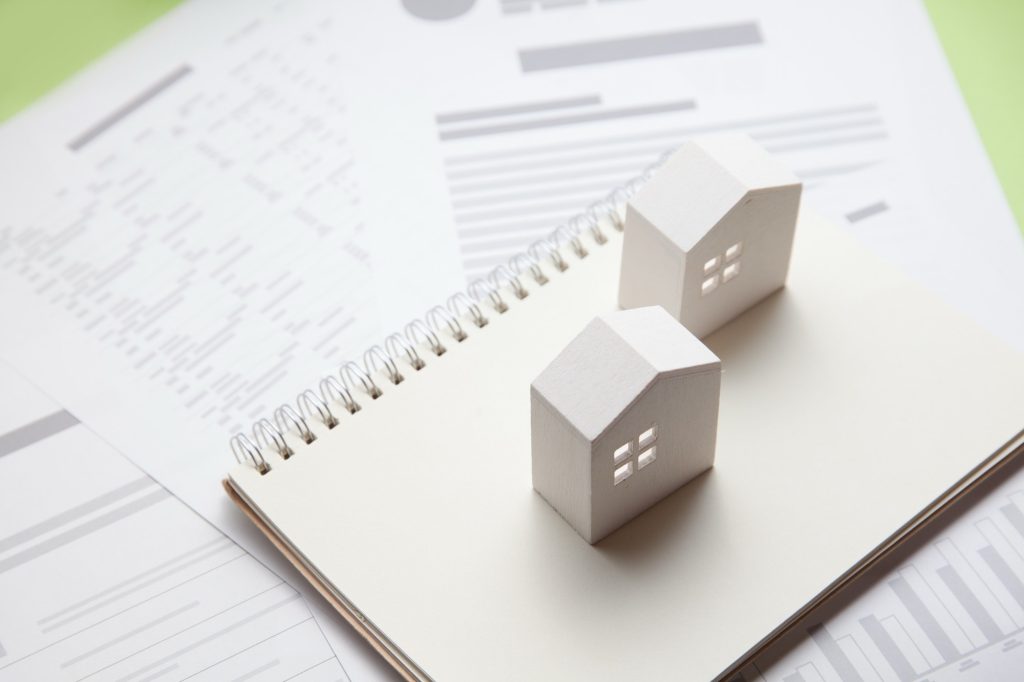 住宅模型とメモ帳、資料のイメージ
