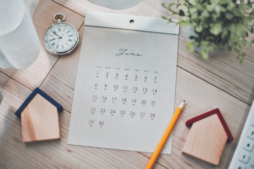 カレンダーとミニチュア木製の家と電卓