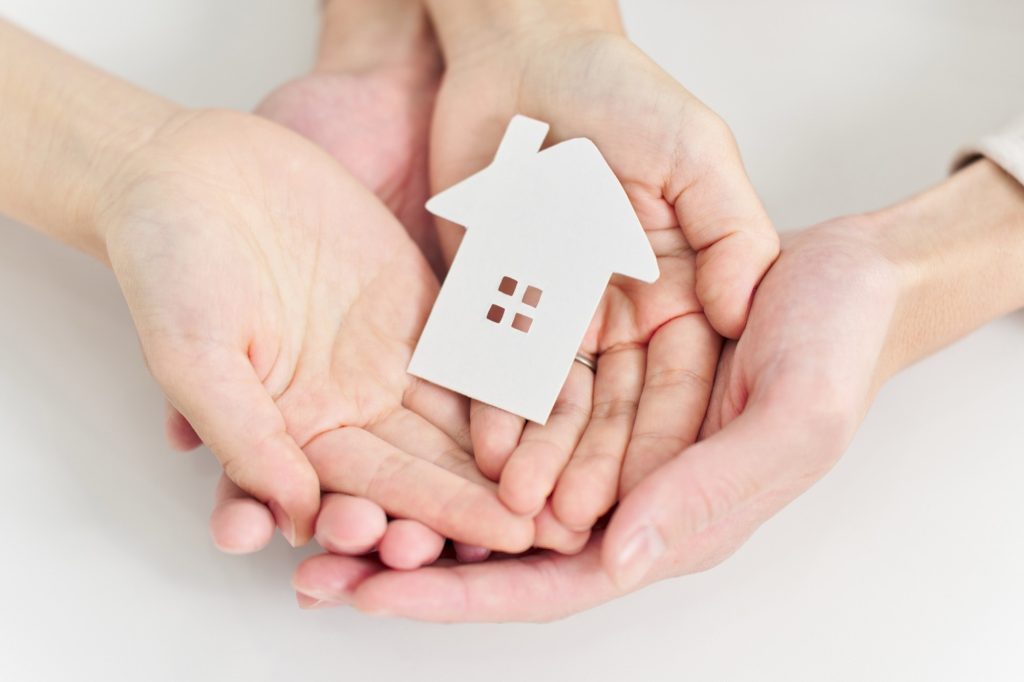 家のオブジェを乗せる男女の手