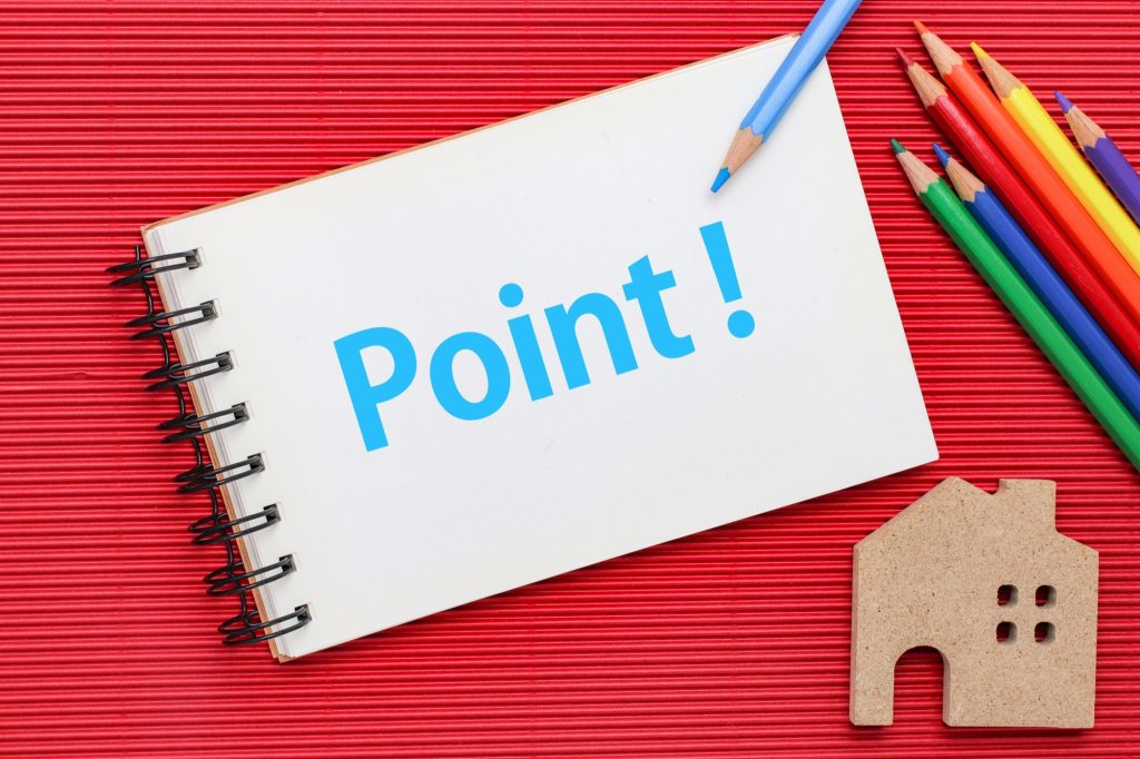 スケッチブックに描かれたPOINTと色鉛筆、木の家