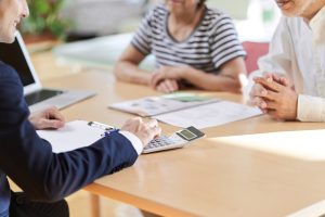 電卓で計算をする不動産会社スタッフと顧客
