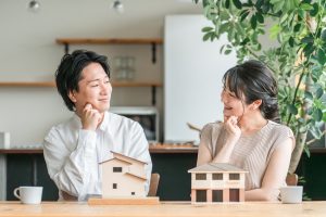 住宅模型の前で会話する夫婦