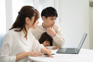相続に関する書類について調べながら書く女性とその家族
